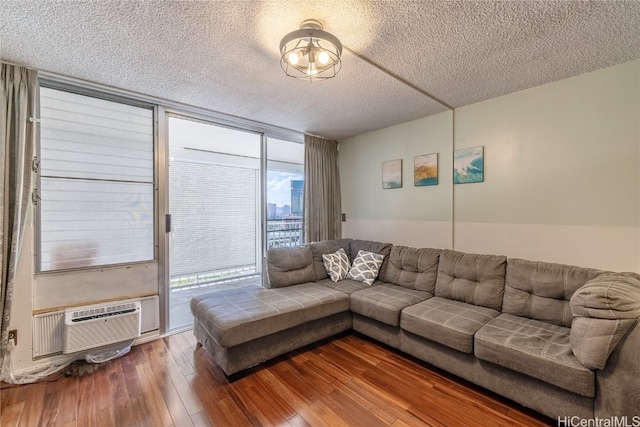 living room featuring a wall mounted air conditioner, a wall of windows, a textured ceiling, and wood-type flooring