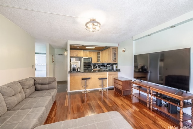 living room with a textured ceiling, stacked washer / dryer, and dark wood-type flooring