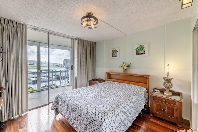 bedroom with expansive windows, a textured ceiling, hardwood / wood-style flooring, and access to exterior