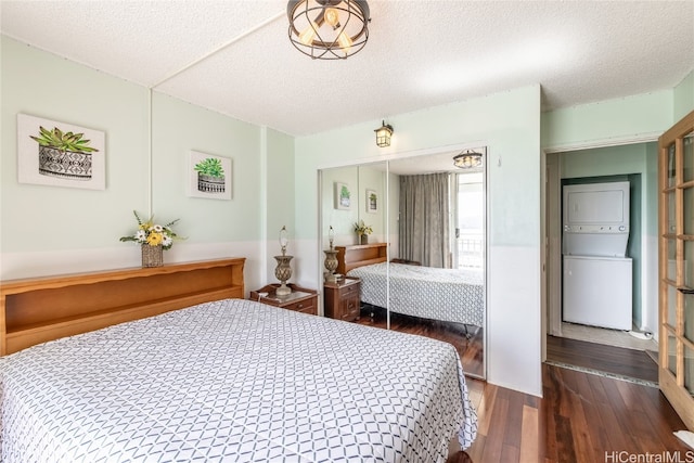 bedroom with dark wood-type flooring, a closet, a textured ceiling, and stacked washer and dryer