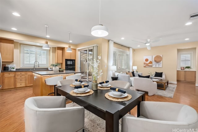 dining space featuring ceiling fan, sink, and light hardwood / wood-style flooring