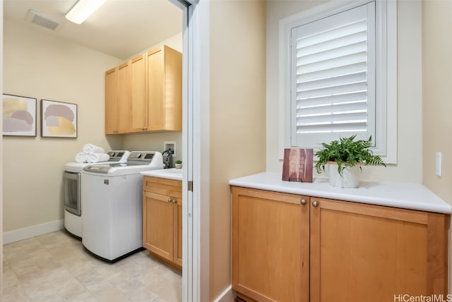 clothes washing area featuring cabinets and separate washer and dryer