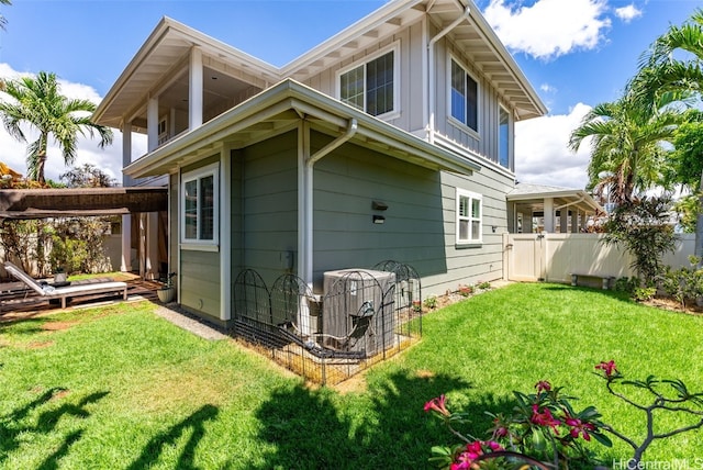 rear view of house with a lawn and cooling unit