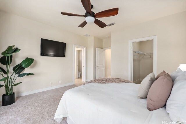 carpeted bedroom featuring ceiling fan, ensuite bath, a spacious closet, and a closet