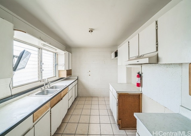 kitchen featuring light tile patterned flooring, white cabinetry, sink, and tile walls