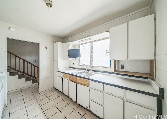 kitchen with white cabinetry, sink, and light tile patterned floors