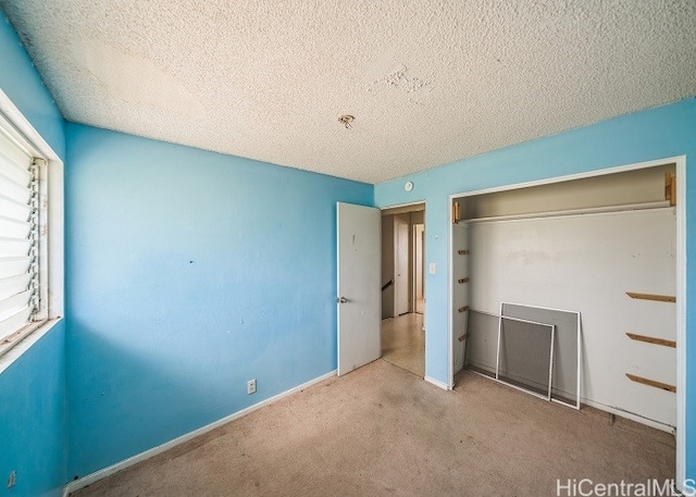 unfurnished bedroom featuring light carpet, a textured ceiling, and a closet