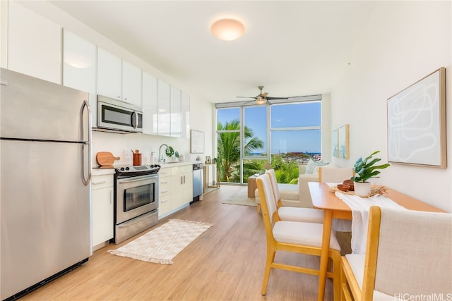 kitchen with appliances with stainless steel finishes, white cabinetry, ceiling fan, and light hardwood / wood-style floors