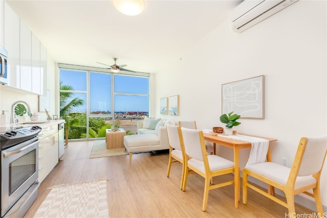 dining room featuring a wall unit AC, ceiling fan, light wood-type flooring, a wall of windows, and sink