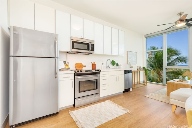 kitchen with appliances with stainless steel finishes, sink, ceiling fan, light hardwood / wood-style floors, and white cabinets