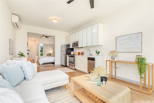 living room with ceiling fan, a wall mounted AC, sink, and light wood-type flooring