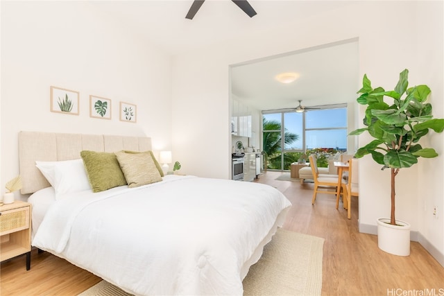 bedroom with expansive windows, light wood-type flooring, and ceiling fan