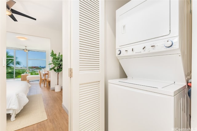 washroom featuring stacked washer / dryer, light hardwood / wood-style floors, and ceiling fan