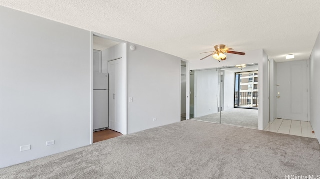 empty room with ceiling fan, carpet, and a textured ceiling