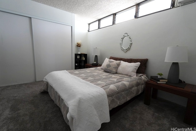 bedroom with a closet, a textured ceiling, and dark carpet