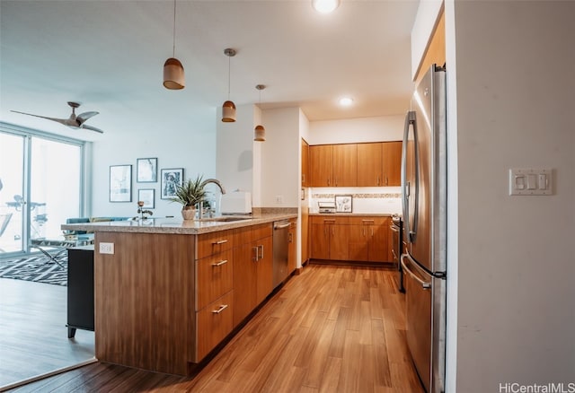 kitchen featuring light hardwood / wood-style floors, appliances with stainless steel finishes, sink, and kitchen peninsula