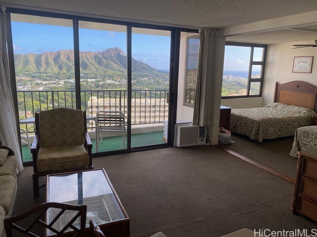 bedroom featuring access to outside, a mountain view, a textured ceiling, and carpet floors