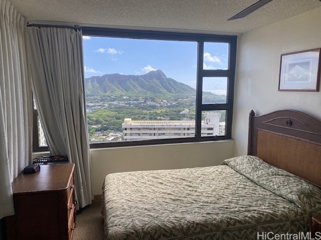 bedroom with carpet flooring, a mountain view, a textured ceiling, and ceiling fan