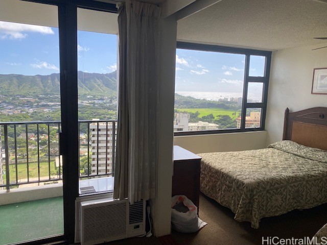 bedroom with multiple windows, a mountain view, and a textured ceiling