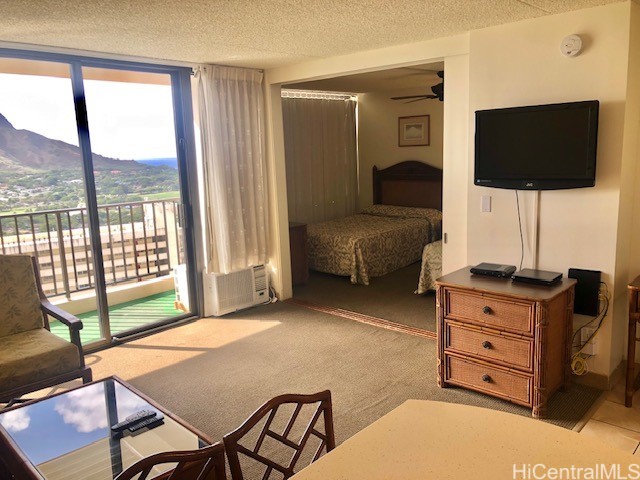 bedroom with a textured ceiling, a mountain view, access to exterior, and light colored carpet