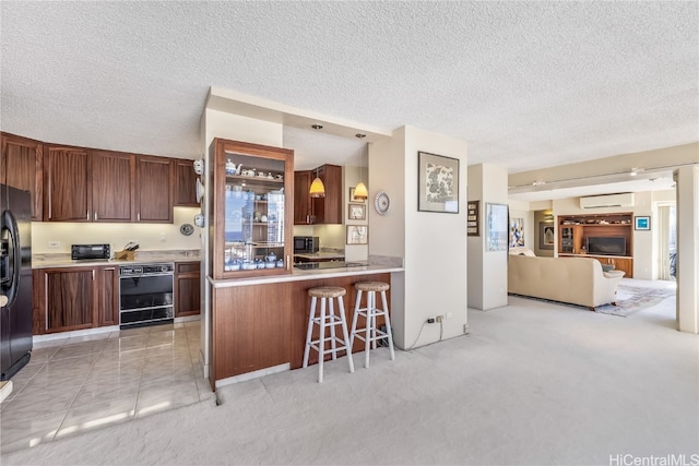 kitchen featuring kitchen peninsula, a textured ceiling, light colored carpet, and a breakfast bar area