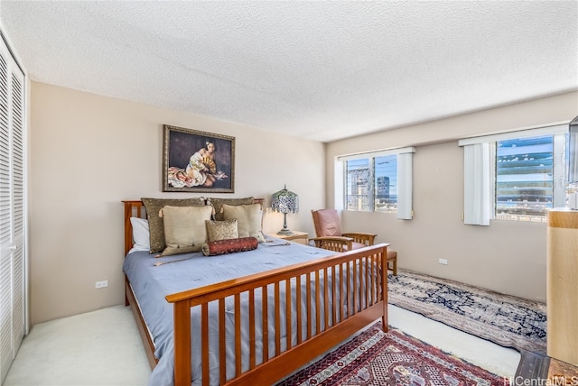 carpeted bedroom featuring multiple windows, a textured ceiling, and a closet