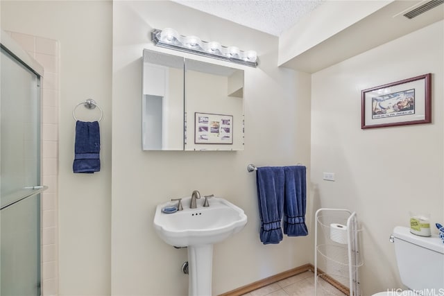 bathroom featuring toilet, tile patterned flooring, sink, a textured ceiling, and walk in shower