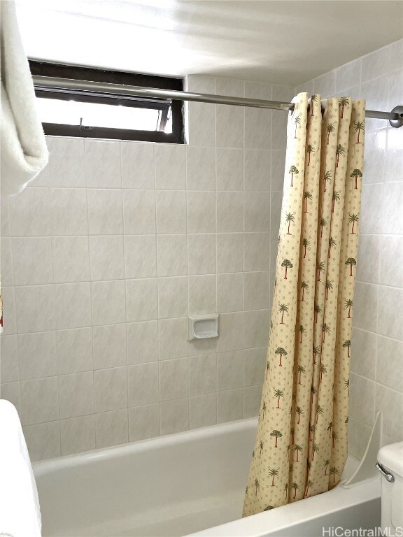 bathroom with shower / tub combo with curtain and toilet