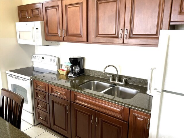 kitchen with white appliances, light tile patterned floors, sink, and dark stone counters