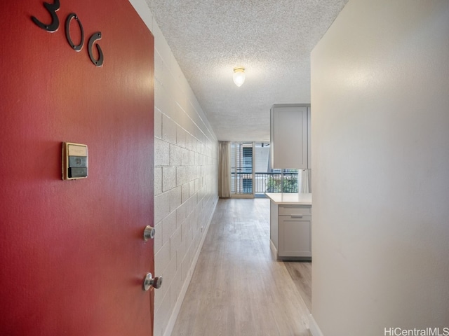 hallway with light hardwood / wood-style flooring and a textured ceiling