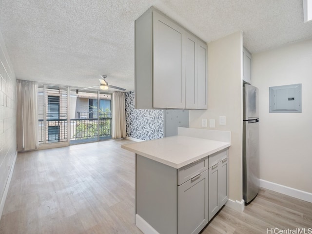 kitchen featuring stainless steel fridge, ceiling fan, a textured ceiling, light hardwood / wood-style flooring, and gray cabinetry