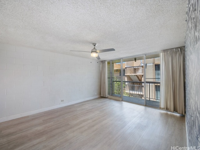 unfurnished room featuring light hardwood / wood-style floors, a textured ceiling, a wall of windows, and ceiling fan