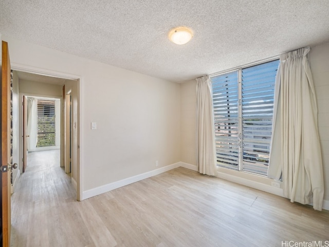 empty room featuring a textured ceiling and light hardwood / wood-style flooring