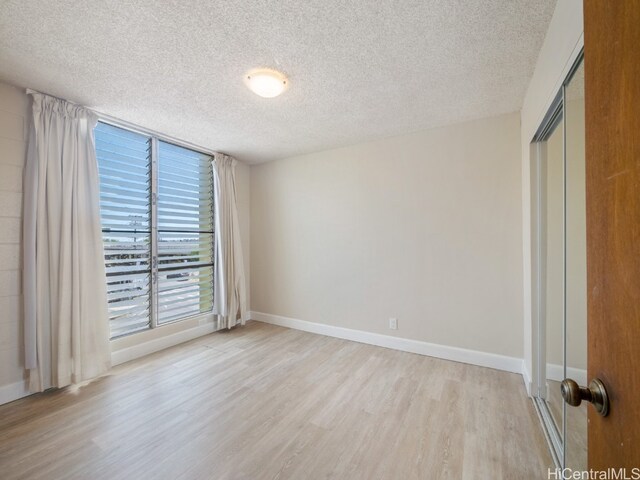 unfurnished bedroom featuring light hardwood / wood-style flooring, a textured ceiling, and a closet