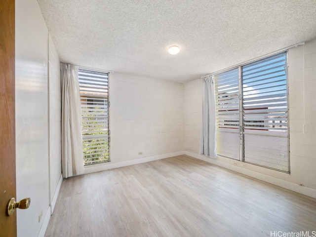 empty room with light hardwood / wood-style floors and a textured ceiling