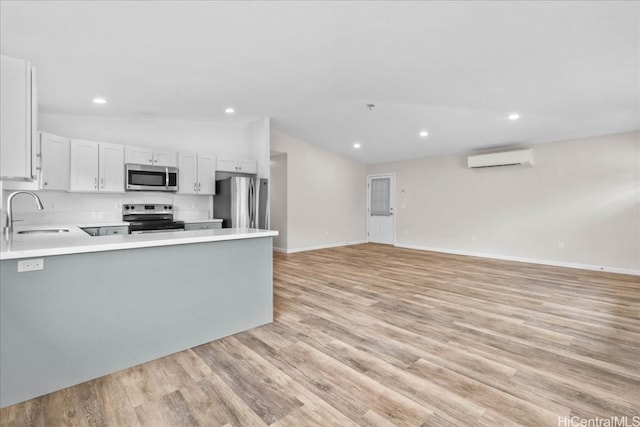 kitchen with lofted ceiling, stainless steel appliances, sink, light wood-type flooring, and white cabinetry