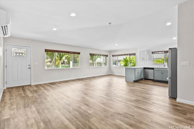 unfurnished living room featuring a wall mounted AC and light hardwood / wood-style floors