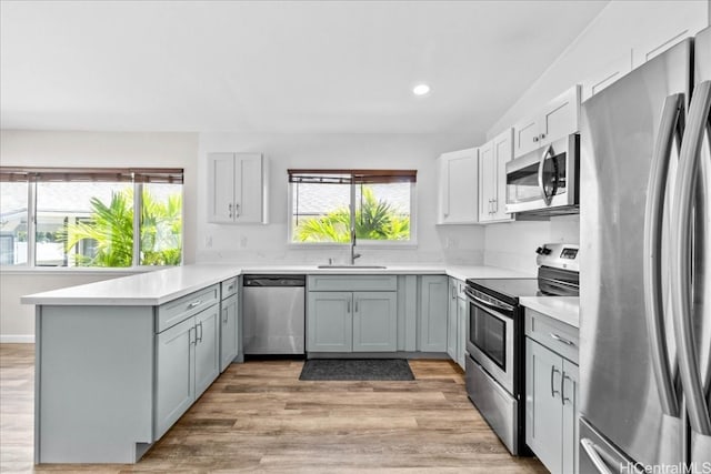 kitchen featuring light hardwood / wood-style flooring, gray cabinetry, stainless steel appliances, and kitchen peninsula