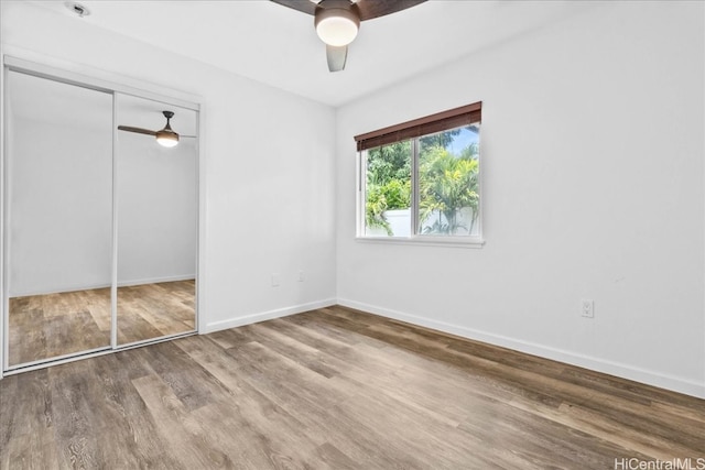 unfurnished bedroom with hardwood / wood-style flooring, a closet, and ceiling fan