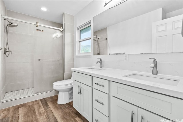 bathroom featuring vanity, toilet, a shower with door, and hardwood / wood-style floors