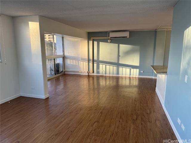 unfurnished living room featuring dark wood-type flooring, a wall mounted AC, and a textured ceiling