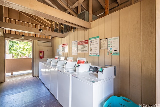 clothes washing area with wood walls and washing machine and clothes dryer