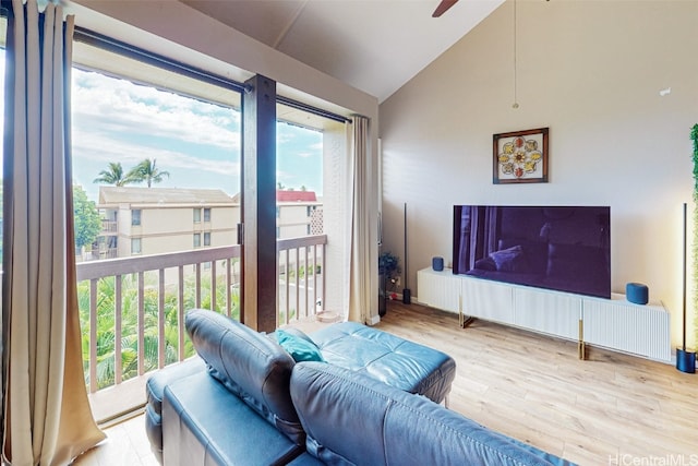 living room featuring light hardwood / wood-style floors, lofted ceiling, a wealth of natural light, and ceiling fan