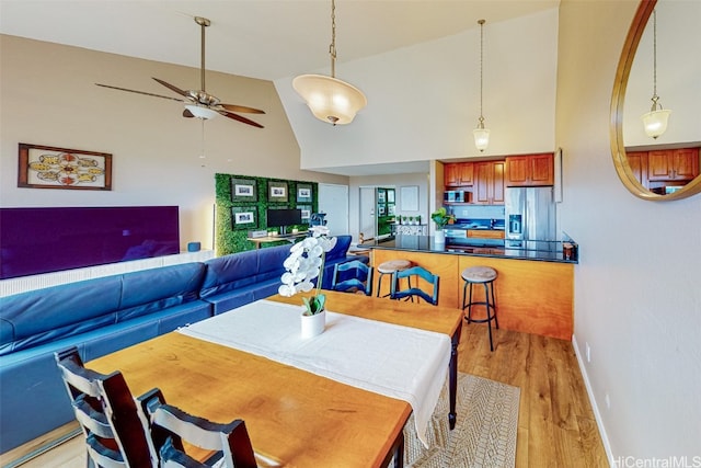 dining area featuring light hardwood / wood-style floors, high vaulted ceiling, and ceiling fan