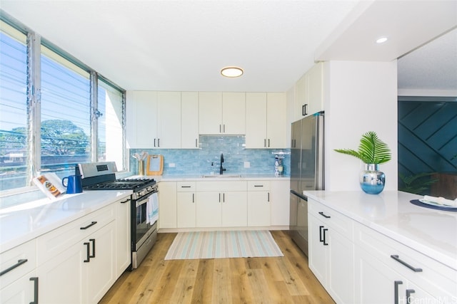 kitchen with sink, backsplash, white cabinetry, light hardwood / wood-style floors, and stainless steel appliances