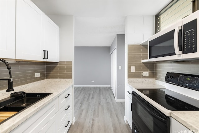 kitchen with a sink, light wood-style floors, white microwave, white cabinets, and electric range
