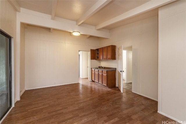 unfurnished living room with dark hardwood / wood-style floors, beam ceiling, and sink