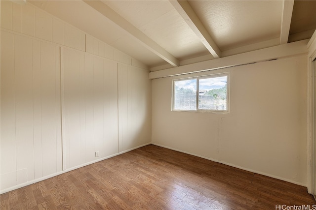 unfurnished room featuring hardwood / wood-style floors and lofted ceiling with beams