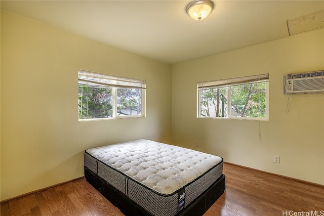 bedroom featuring a wall mounted AC and hardwood / wood-style floors