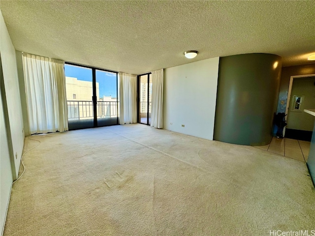 empty room with light carpet, a textured ceiling, and floor to ceiling windows